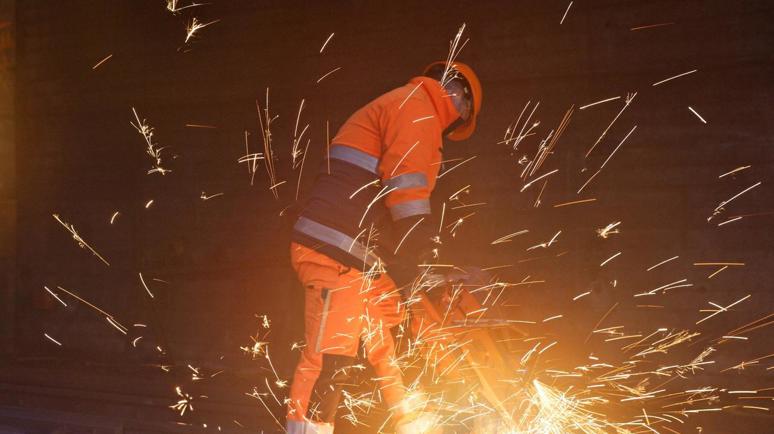 Un employé des CFF en tenue de travail orange en train de souder